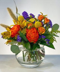 This enchanted fall arrangement will surely bright your table with circus roses, yellow craspedia, orange spray, yellow asltroemeria, millet and touch of purple in a lovely bubble bowl. 