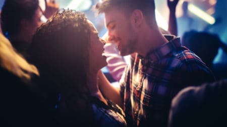 Young Beautiful Couple Enjoying Time Together in Crowd at a Rock Band Concert. Handsome Man and Pretty Woman are in Love at a Gig in Bright Colorful Strobing Lights on Stage.